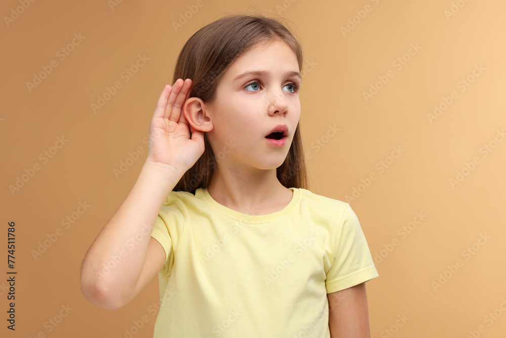 Little girl with hearing problem on pale brown background Little girl with hearing problem on pale brown background