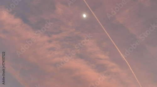 La luna al tramonto risplende tra le nuvole nella luce del giorno photo