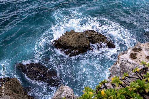 Jagged cliffs weathered by water, wind, and time meet the rough turquoise waters of the Pacific Ocean along the Mahaulepu Heritage Trail in Koloa, Hawaii on the island of Kauai. photo