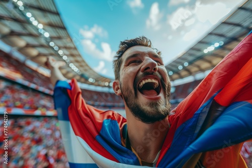 A man is holding a red, white, and blue flag and smiling. Football fans or spectators at the football championship © top images