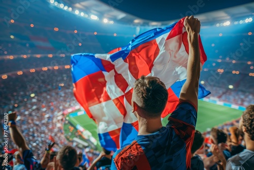 A man is holding a flag in a stadium full of people. Football fans or spectators at the football championship photo
