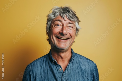 Portrait of a happy senior man with grey hair on yellow background