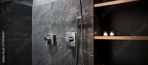 A modern shower with a sleek black tiled wall and a rustic wooden shelf for bath essentials