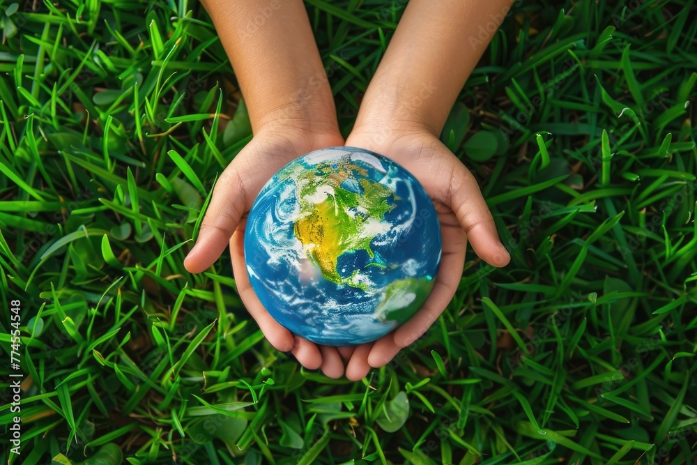Small children's hands with a model of the globe on a grass background. Small children's hands with a model of the globe on a grass background.