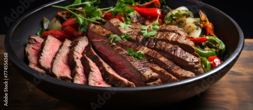 On a wooden table, there is a close-up view of a bowl filled with a delicious mix of steak and colorful vegetables