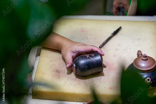 A traditional craftsman is carving and making a Chinese purple sand tea cup