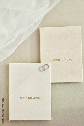 Elegant wedding rings rest on ‘WEDDING VOWS’ booklets photo