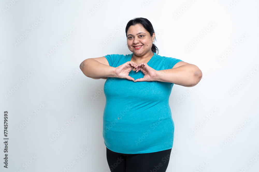 Smiling overweight indian woman shapes heart with both hands against white background. Asian Plus size female expresses love, Relationship, expressing kindness, health care concept, Copy Space Smiling overweight indian woman shapes heart with both hands against white background. Asian Plus size female expresses love, Relationship, expressing kindness, health care concept, Copy Space