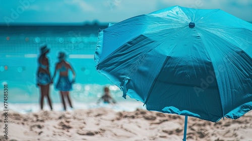 Summer Vibes: A blue beach umbrella stands out against the playful backdrop of seaside fun. © Alex