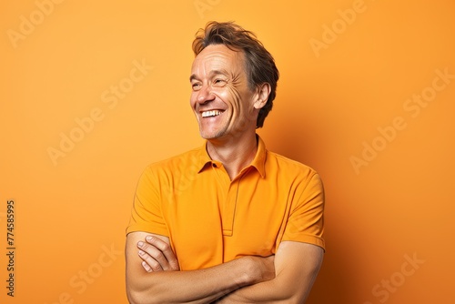 Portrait of happy mature man with crossed arms on orange background. © Stocknterias