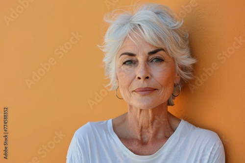 Portrait of a beautiful senior woman with grey hair against orange wall