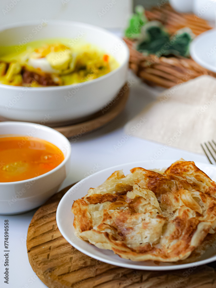 Roti Parata or Roti canai with curry sauce, a popular Malaysian breakfast Roti Parata or Roti canai with curry sauce, a popular Malaysian breakfast