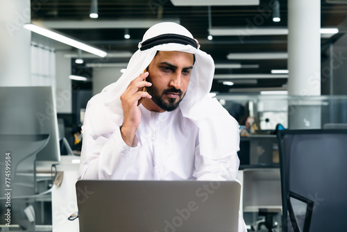 Arab Middle East man at modern office wearing Kandura dishdash traditional menswear. Arabic person corporate concept. Arabian local national on mobile smart phone device