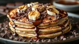   A plate of pancakes smothered in chocolate and topped with banana slices and drizzled with chocolate chips