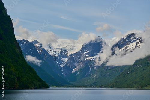 tranquil and calm Oldevatnet glacial lake in front of the melting Briksdalsbren glacier in Norway with snow capped mountains. photo