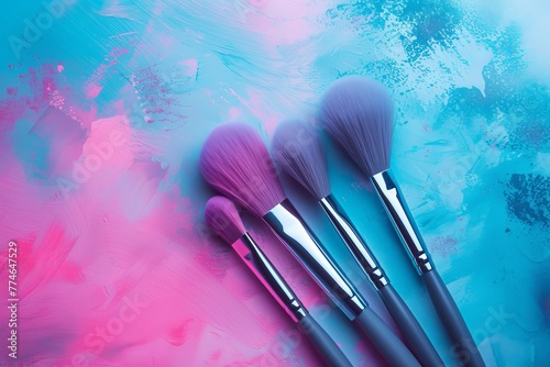   Three makeup brushes atop a blue-pink spatula against a pink-blue backdrop photo