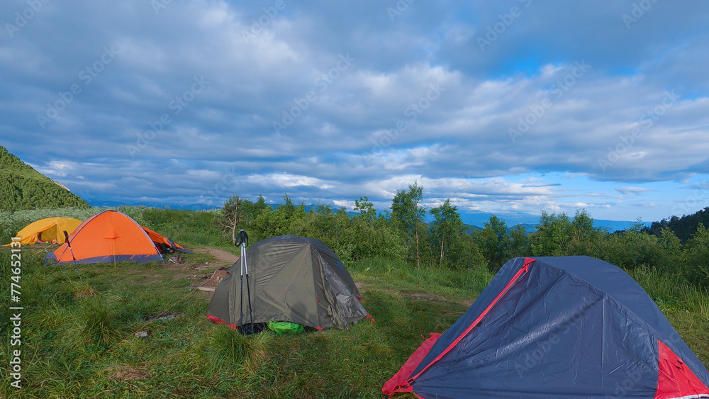 Four tents pitched in a scenic outdoor mountain setting. Group mountain hike.