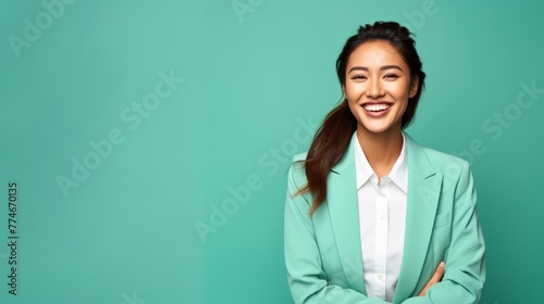 A successful East Asian businesswoman in her late 20s, against a gentle mint green background, flashing a radiant smile © Hanna Haradzetska