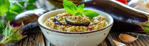 A white bowl filled with baba ganoush made from baked eggplant with sesame paste, placed on a wooden table photo