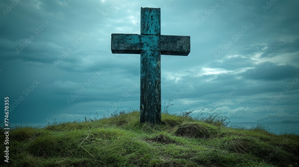   A large wooden cross atop a green hill, surrounded by clouds, with a blue sky peeking through