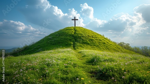  A cross atop a hill, surrounded by grass and wildflowers in the foreground, and a blue sky with scattered clouds in the background