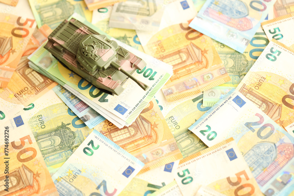 Many euro banknotes and tank. Lot of bills of European union currency and green tank close up