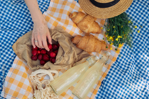 Delightful picnic spread: croissants, strawberries, lemonade on checkered blanket. © phpetrunina14