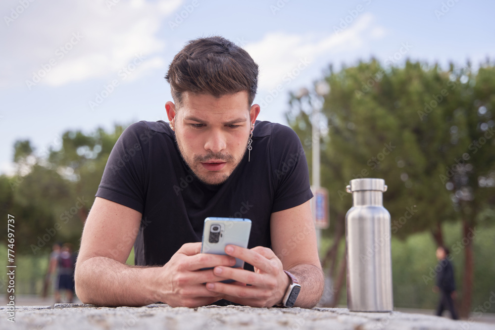 young millennial man looking at his smart phone young millennial man looking at his smart phone