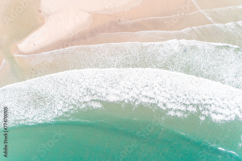 aerial drone top view of a white sandy beach on the shores of a beautiful turquoise sea.