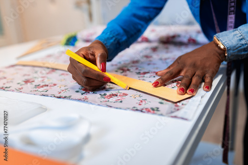 Close up of female fashion tailor hands working on the measurements for the dress design in her workshop.