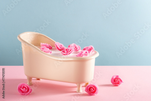 Bath full of water with soap foam with roses on pink and blue background. Minimal spa card. photo