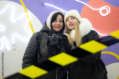 Two women are taking pictures of their reflection in the mirror 