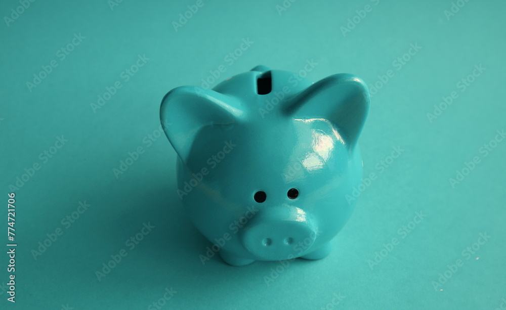 Stylish modern piggy bank on a turquoise background closeup