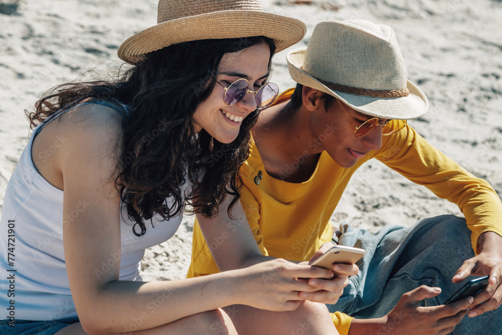 young couple using smartphone on the beach