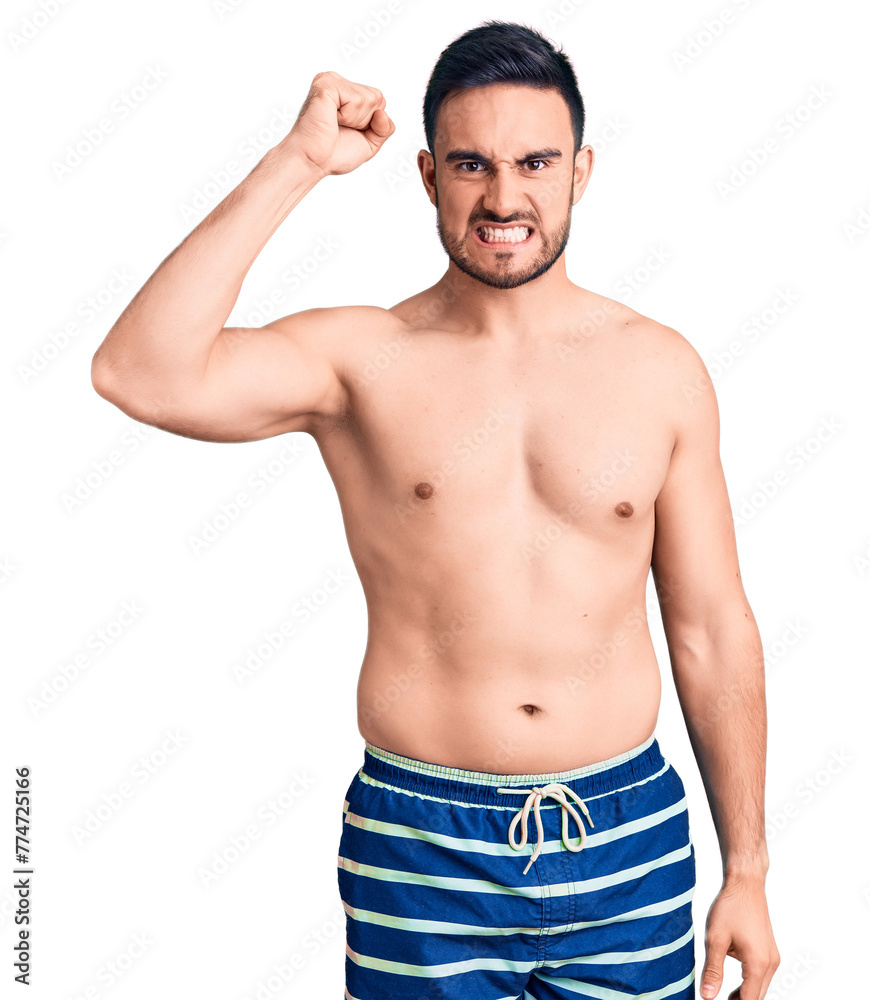 Fototapeta premium Young handsome man wearing swimwear angry and mad raising fist frustrated and furious while shouting with anger. rage and aggressive concept.