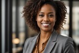 A woman with curly hair is smiling and wearing a business suit