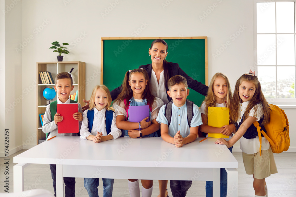 Group portrait of first graders with friendly female teacher in school ...