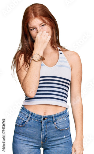 Young read head woman wearing casual clothes smelling something stinky and disgusting, intolerable smell, holding breath with fingers on nose. bad smell