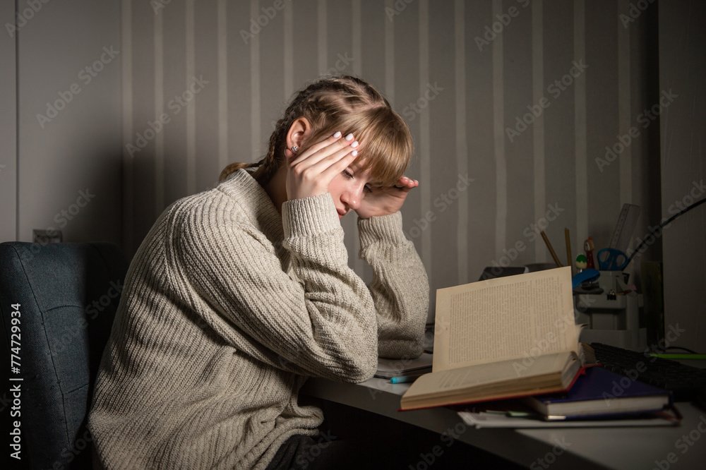 An overworked student falls asleep reading a book in the dark. Overtime processing. Study after work An overworked student falls asleep reading a book in the dark. Overtime processing. Study after work