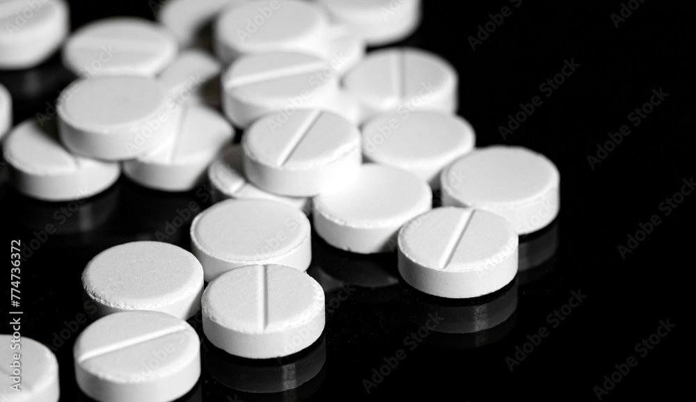 Close up of white painkiller tablet on a reflective black backgr Close up of white painkiller tablet on a reflective black backgr