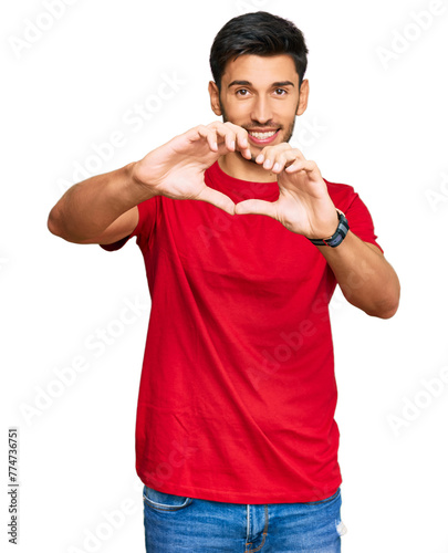 Young handsome man wearing casual red tshirt smiling in love doing heart symbol shape with hands. romantic concept.