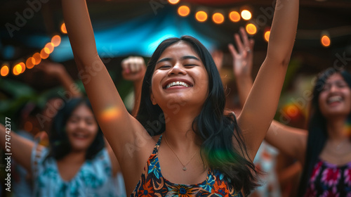 Cheerful young latin girl dancing at a summer music festival at night.