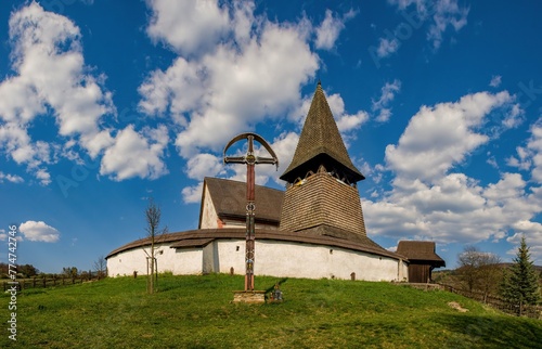 Old wooden historic fortified church, sunny day during early spring, blue sky with clouds. The village of Cerin near Banská Bystrica, Slovakia photo