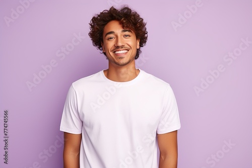 A man with a white shirt and curly hair is smiling at the camera