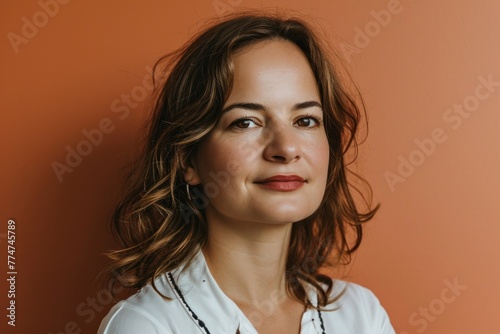 Portrait of a beautiful young woman in a white shirt on an orange background