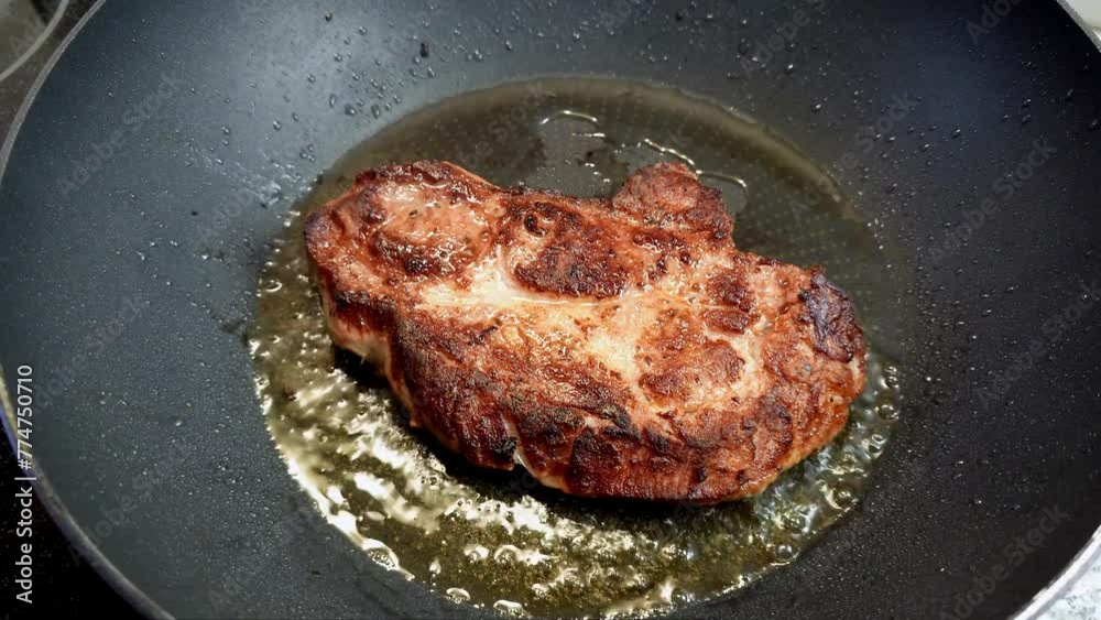Pork steak filet is being home cooked in a frying pan. Top view, close up shot, real time, no people Pork steak filet is being home cooked in a frying pan. Top view, close up shot, real time, no people