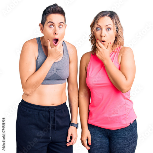 Couple of women wearing sportswear looking fascinated with disbelief, surprise and amazed expression with hands on chin
