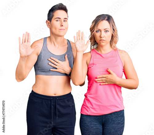Couple of women wearing sportswear swearing with hand on chest and open palm, making a loyalty promise oath