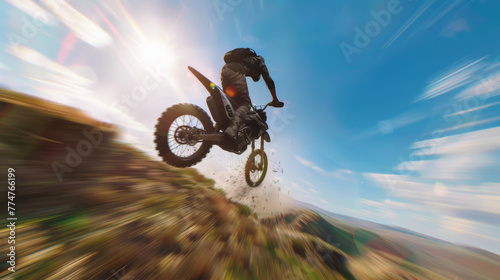 A motocross rider in mid-jump on a dirt track, with motion blur emphasizing speed and motion against a clear sky. © Moopingz