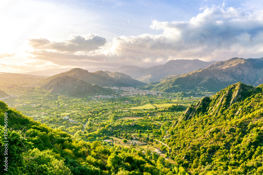 Naklejka premium amazing highland view from above to a canyon and valley between mountains and green hills, cloudy sunset landscape of beautiful highland